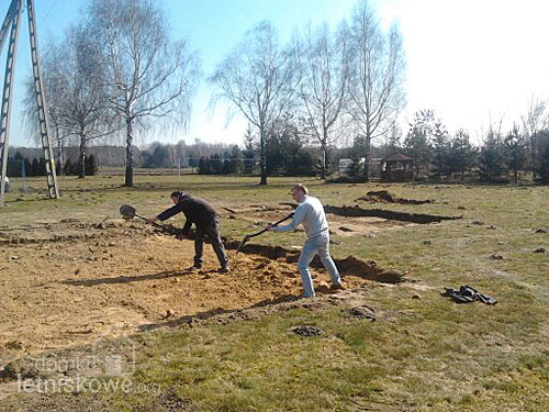 - Nałożenie pierwszej warstwy piasku - przygotowanie podłoża dla domku drewnianego - domkiletniskowe.org