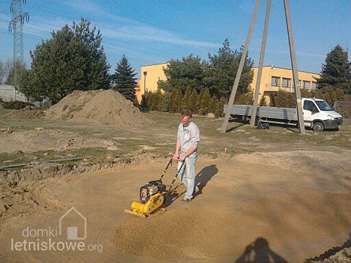 - Wibrowanie pierwszej warstwy piasku - przygotowanie podłoża dla domku drewnianego - domkiletniskowe.org