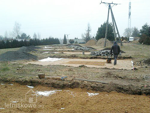 Wibrowanie kolejnej warstwy piasku - przygotowanie podłoża dla domku drewnianego - domkiletniskowe.org